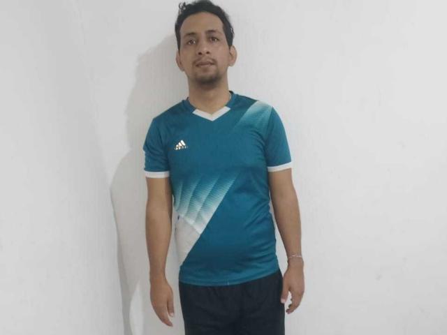 RobinsonSexlv stands in a plain white room, wearing a teal Adidas soccer shirt with diagonal white and blue gradients, and black pants, looking slightly to the right.