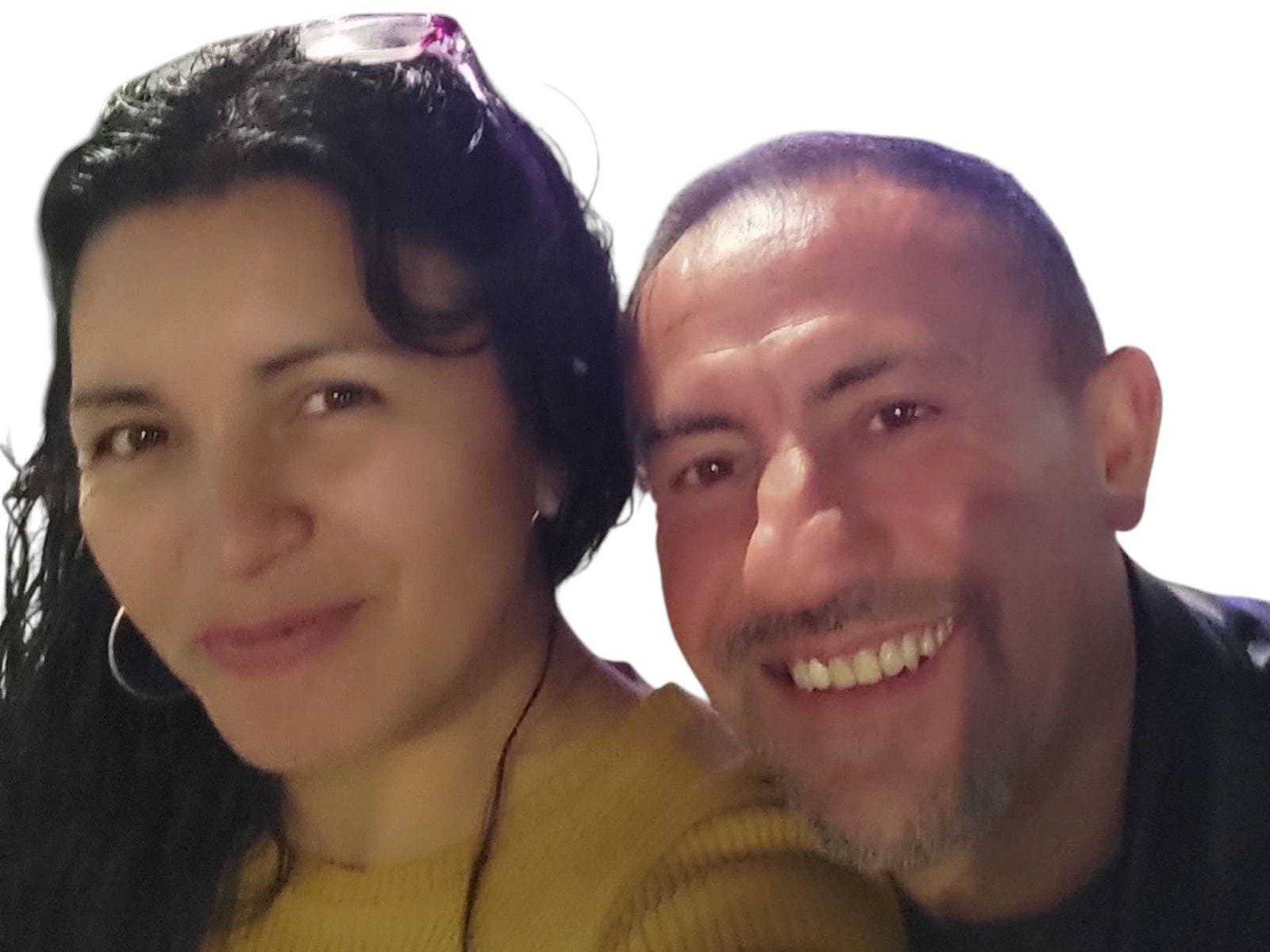 PuroFuego with dark curly hair, hoop earrings, and yellow sweater, next to PuroFuego with shaved head, beard, and black shirt, smiling. Both have light skin and brown eyes.