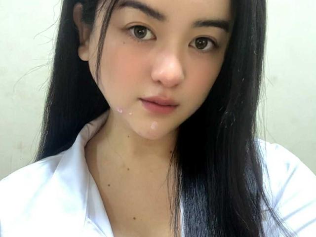 YourSophie ha lunghi capelli neri, occhi marroni e un viso leggermente arrossato con del liquido bianco sul mento. Indossa una camicia bianca e guarda verso la fotocamera..