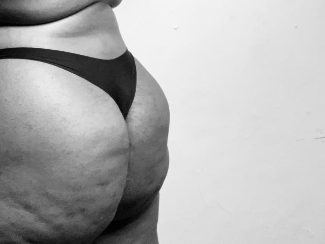 SpiceBomb's fat, round ass in black thong, showing prominent butt cheeks and visible skin texture in a black-and-white photo.