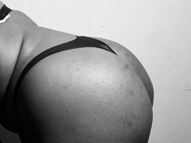 SpiceBomb's big ass in black thong, showing a lot of butt and some butt pimples, in a black-and-white photo.