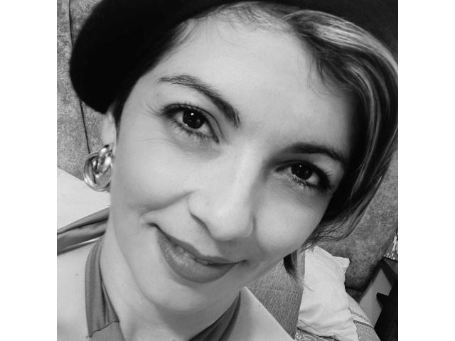 ChanelJolie has short brown hair, a black beret, and is smiling with her lips slightly parted. She's wearing a shirt and has a nose ring and earrings.