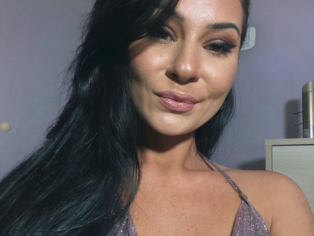 PrettyA with shiny black hair, subtle makeup, and pink lips, wearing a glittery halter top, showing off her shiny, smooth, tan skin and slightly visible tits.