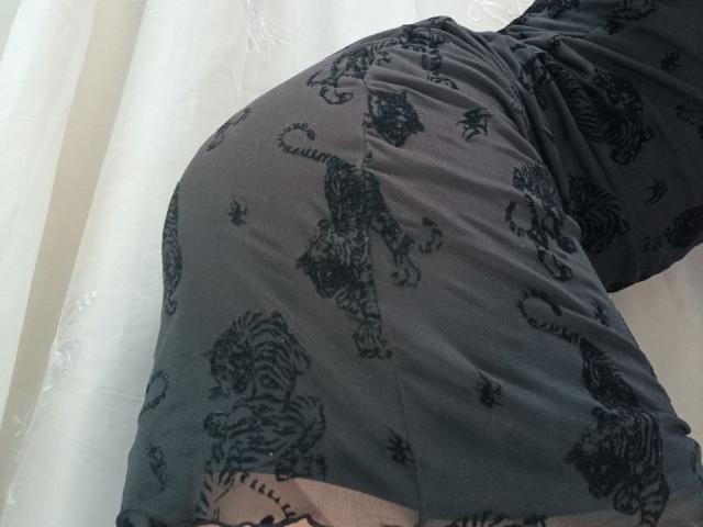 WollyMolly's ass in a tight, dark gray dress with black tiger and dragon patterns. The dress is slightly bunched, showing a bit of her upper thigh and tattoo.