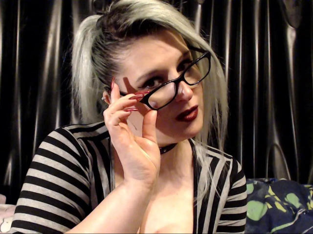Avengelique-hot with blonde and black hair in a ponytail, wearing glasses, striped top, and choker, touching glasses, showing her tits, with dark lipstick.