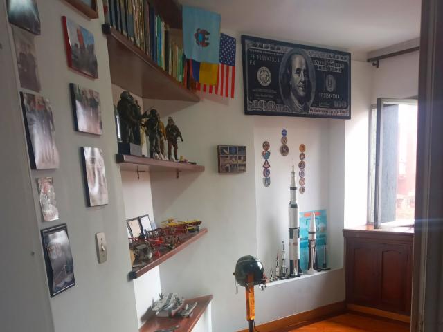 Een kamer met witte muren, een houten vloer en planken. Op de planken staan modellen, militaire figuurtjes en vlaggen. Een raam laat licht binnen. Op de muur hangt een poster van Martin Luther King Jr..