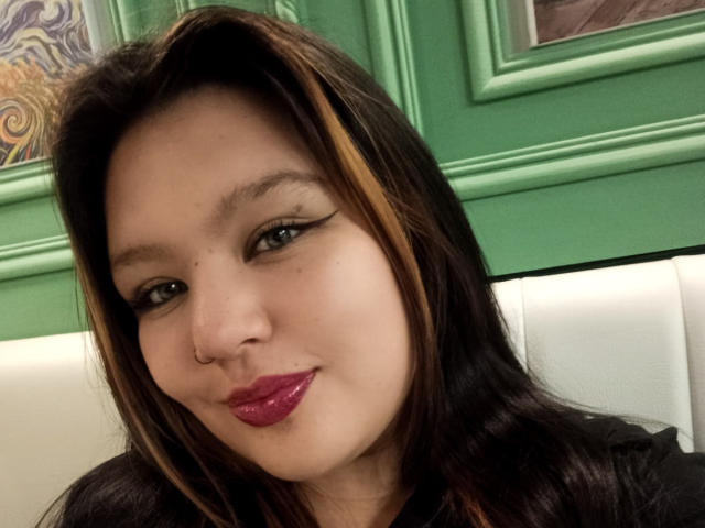 CaroHotcg has a cute face with dark brown hair, a nose ring, and glossy pink lips. She's wearing black eyeliner and looking at the camera with a slight smile.