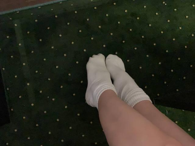 MoonLiza's legs with white socks, feet together, on a green polka-dotted carpet. Socks are slightly wrinkled, covering her ass. No visible shoes or boots.