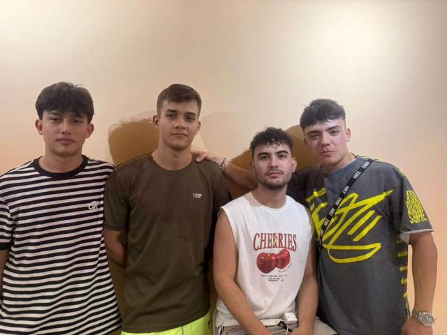Quatre SpaceMen69 debout en rang, portant des chemises rayées, marron, blanches et grises, dont l'un a un t-shirt avec un motif jaune et un pantalon vert néon. Le SpaceMen69 au centre..