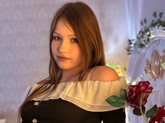 Bubochka with light brown hair, wearing a black top with a white ruffled collar, has small tits, a cute face, and is holding a red rose.