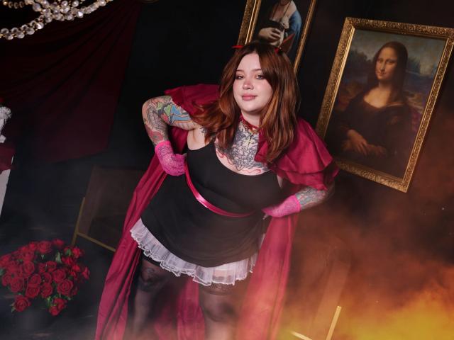 YoureGift with red hair, tattoos, black dress, white lace, pink gloves, red cape, standing, red roses, painting of woman, candle, dark room, you're looking hot and fierce, baby.