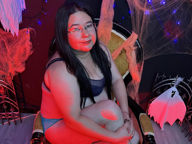 Hirenne with glasses, black bra, and blue panties, squatting on a chair, red and blue light, black hair, white thigh socks, cute, curvy, fair skin, smiling.