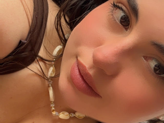 VicluX has a cute face with pink lips, brown eyes, and a slight blush. She's wearing a shell necklace, and her dark brown hair is partially visible.
