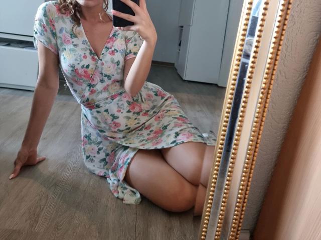 Leilaaa-hot in a floral dress, sitting on wooden floor, knees together, mirror selfie, showing tits and ass, holding phone, curly hair, golden mirror frame, reflection.