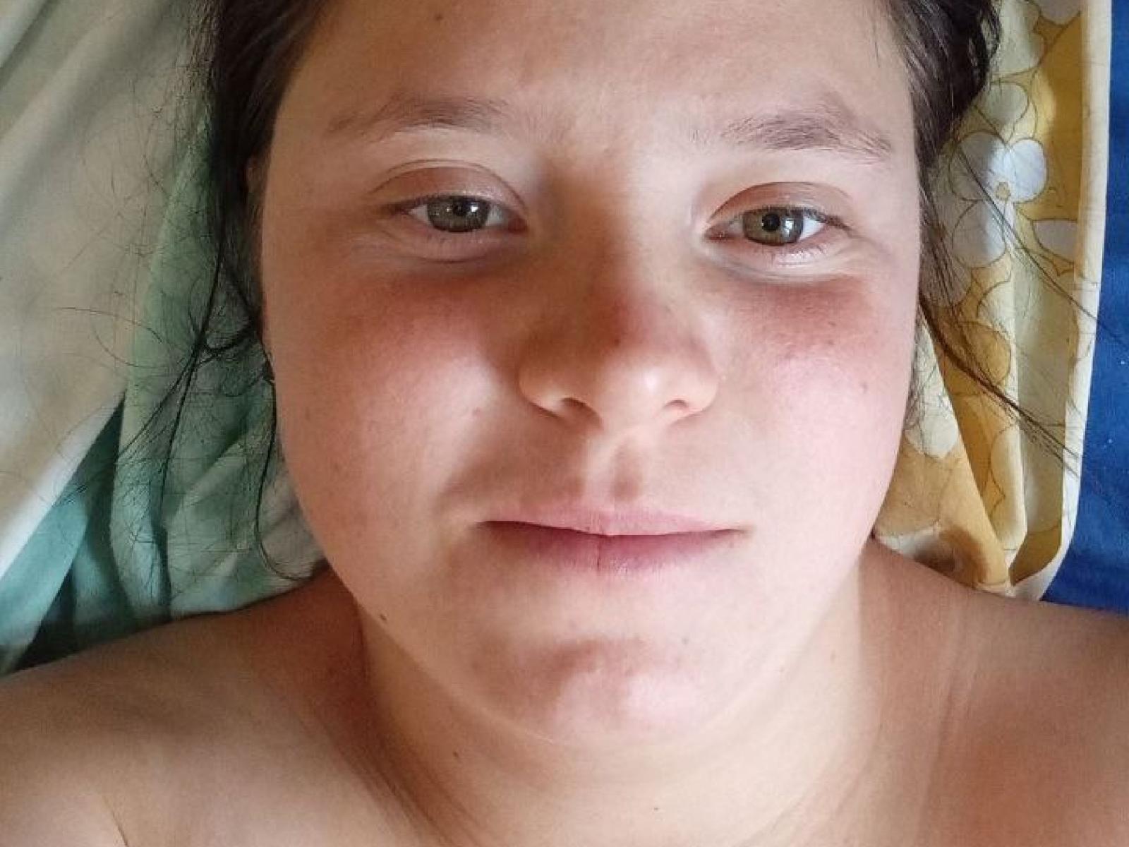 PanbaPanna's face is in the photo, with green eyes, light brown skin, and a slight pout. Her dark hair is messy, and she's lying down, topless.