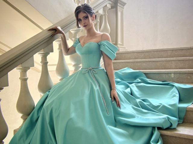Palerianna in a teal off-shoulder dress with puffy sleeves, sitting on stairs, dress pooling around her, holding railing, elegant, sexy, pale skin, brunette, updo.