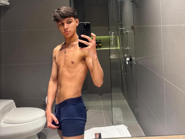 Angelitocute, skinny with a flat chest, wearing navy blue boxer briefs, holding a phone in a mirror selfie, showing a slim, toned, and slightly muscular body.