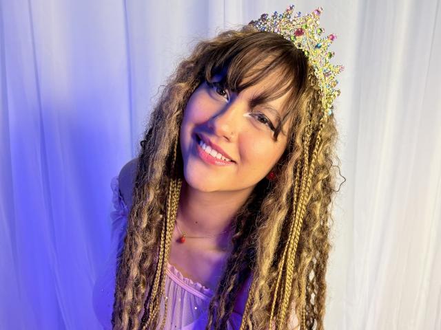 HanaJoud with long curly brown hair, wearing a sparkly tiara, smiling, pink dress, purple light, red necklace, cute, pretty face, happy, attractive.