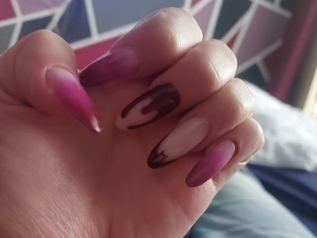 As unhas de JuliaHuntis, longas, afiadas e com um degradê de rosa a magenta, e com espirais marrons escuras no dedo médio, exibem suas unhas brilhantes e bem cuidadas..