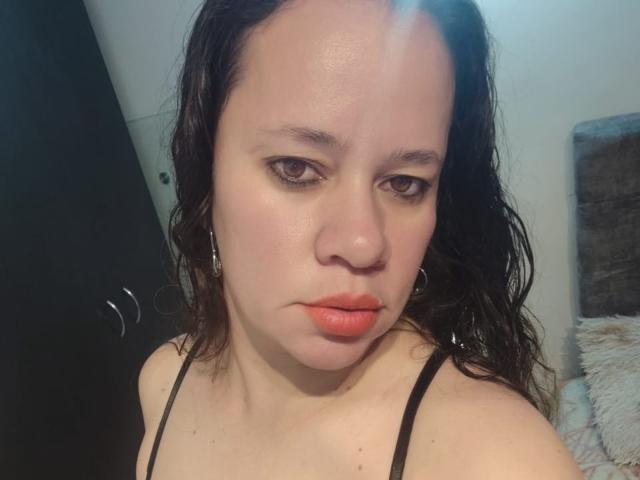 CharllotI tiene el cabello negro y lacio, ojos marrones y lápiz labial naranja. Lleva puesto un top negro con tirantes finos y tiene una expresión seria. Sus pequeños senos redondos son ligeramente visibles..