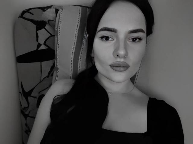 Black-and-white selfie of Lulii69 with dark hair, wearing a beanie and black top, showing her tits slightly visible under her top, with a serious expression and nose piercing.