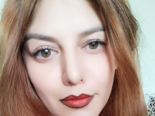 LoreyJolie's face, with light brown eyes, red lipstick, and slightly wavy, dirty blonde hair. Her eyebrows are dark, and her skin is fair. She's looking directly at the camera.