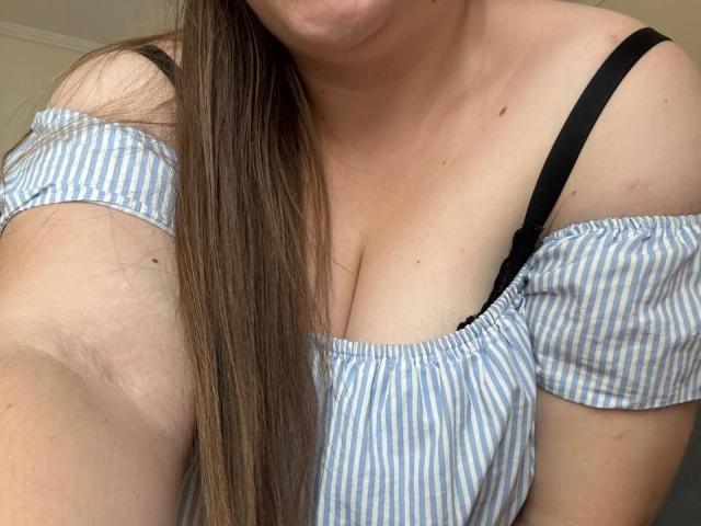 Leiliia with long brown hair, off-shoulder blue and white striped top, black bra strap, showing her tits, slightly visible cleavage, fair skin, upper chest, no face visible.