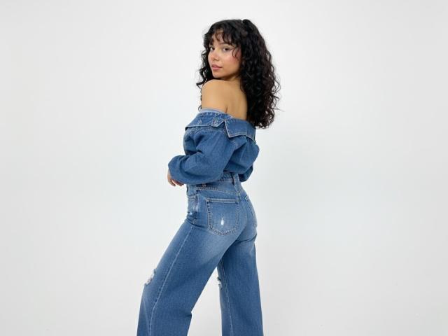 JuliaBennett with curly black hair, off-shoulder blue denim jacket, and high-waisted blue jeans, showing her bare ass and looking back over her shoulder.