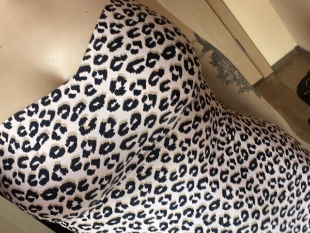 Olieri's leopard-print dress is showing off her big, round, and perky tits, with a tattoo visible on her right side, just above her curvy, sexy ass.