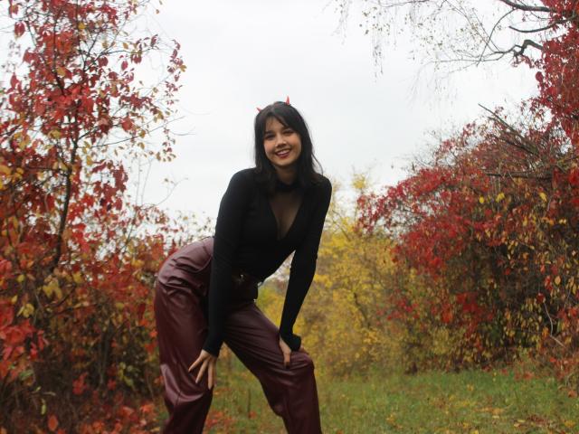 LettyCurly, black turtleneck, deep V, showing tits, burgundy pants, leaning forward, smiling, red leaves, autumn, grass, overcast, black hair, cute, sexy, standing, hands on knees.