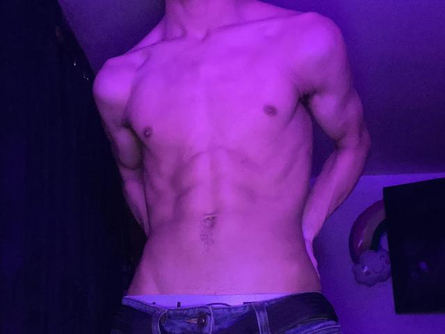 Angelitocute's toned, muscular chest and abs are lit up in purple, wearing unbuttoned jeans with visible underwear, hands on hips, head out of frame.