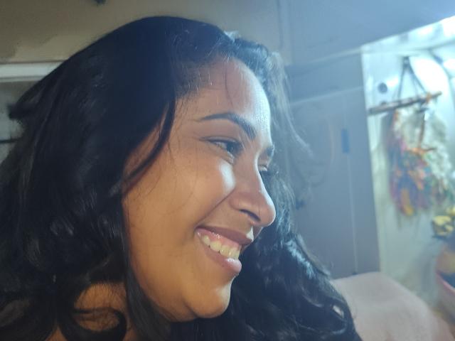 Marinomade has dark wavy hair, brown skin, and a cute smile with visible teeth. She's looking to the side with a playful expression. Her nose is slightly upturned.