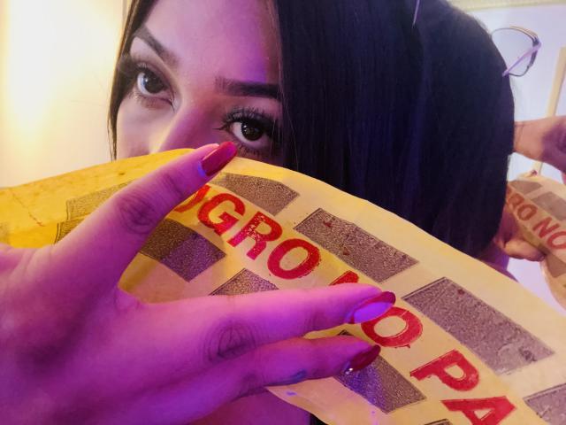 KatianPierce's face with dark hair, purple nail polish, and red nails holding a yellow waffle with "CRUNCH" in red letters, partially covering her eyes.