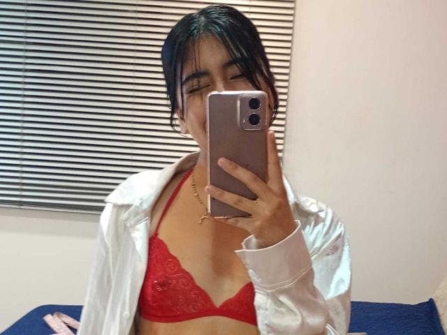 LinaSpearce with black hair, wearing red lace bra and open white shirt, taking mirror selfie with iPhone, showing small tits and slim build.