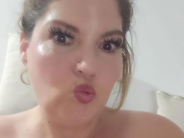 Joyfull-hot, avec une peau brillante, des lèvres roses et pulpeuses, et de longs cils, faisant une moue de canard. Ses cheveux bruns sont légèrement en désordre, et elle est topless..