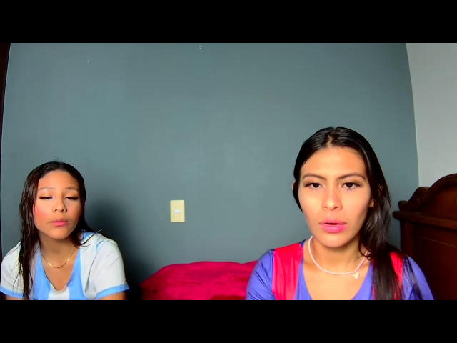 KathyViolet with wet brown hair, pouty lips, wearing a blue and white top, sits left. KathyViolet, with pink lipstick, brown eyes, wearing red and blue top, sits right.