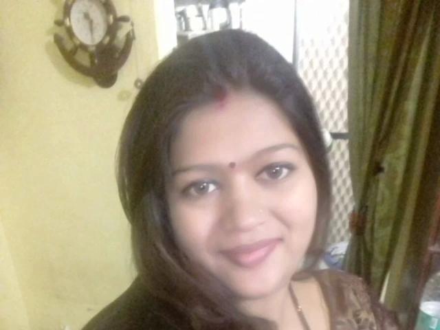 Nehaaahire-hot with dark brown hair, brown eyes, and a small red dot on her forehead, smiling slightly, wearing a brown top, with a small nose ring.