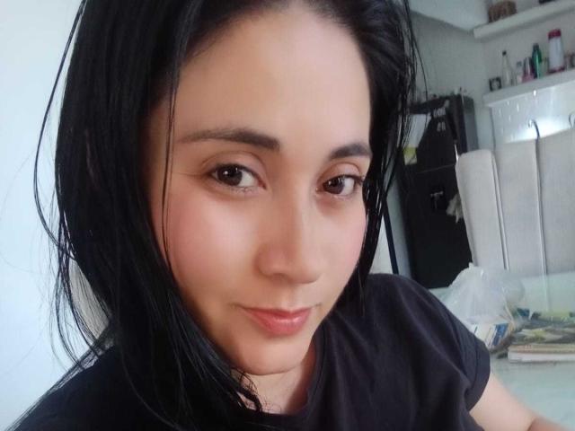 CatalinaGrey has black hair, brown eyes, and a subtle smile. She's wearing a black shirt, with her chin slightly raised. Her skin is light with a natural glow.