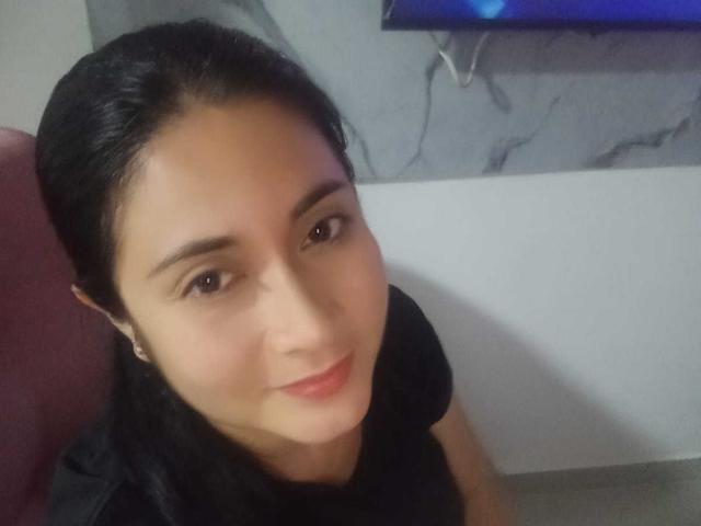CatalinaGrey has dark hair, brown eyes, and a slight smile. She's wearing a black shirt, and her cute face is centered in the photo. Her ass is not visible.