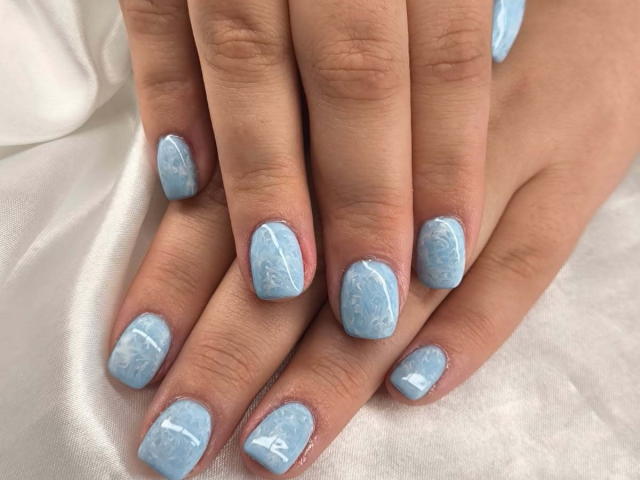 ElvinnaLaFrancaise's hands with blue, marble-patterned, square-shaped nails, showing off cute, glossy, pastel-blue nails on soft, tan skin. Hands are resting on white, silky fabric.