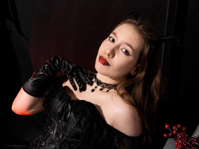  DanielleSweetty with pale skin, red lipstick, black lace corset, and black gloves, wearing a black choker, looking up, brown hair, small red marks on forehead.