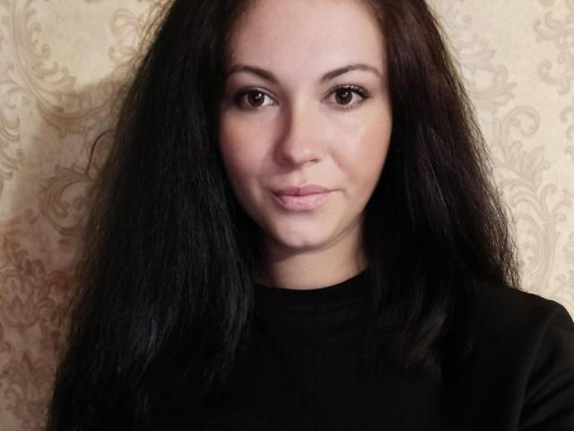 FortuneHelena has long black hair, brown eyes, and a subtle smile. She's wearing a black shirt, with a light, slightly shiny skin tone.