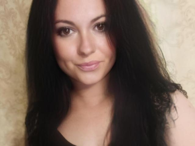 FortuneHelena has long black hair, brown eyes, and a slight smile with pink lips. She's wearing a black top, showing a cute face with subtle makeup.