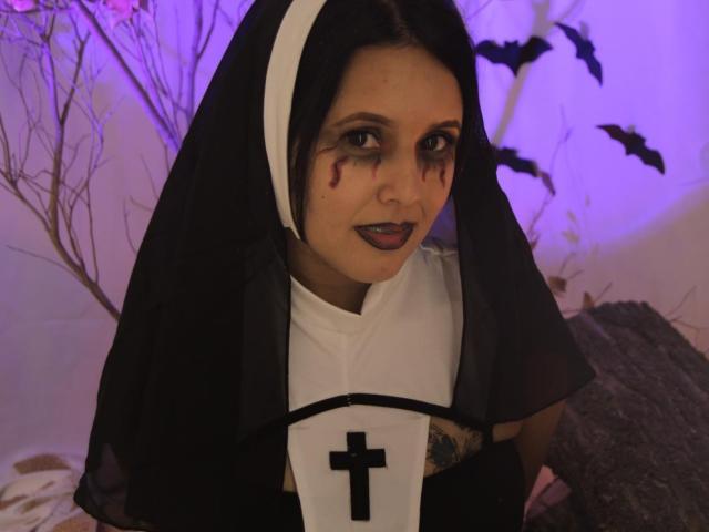 Linger, dressed as a nun, has bloody makeup, black lipstick, and a white cross on a black and white outfit, with a black veil and white headpiece.