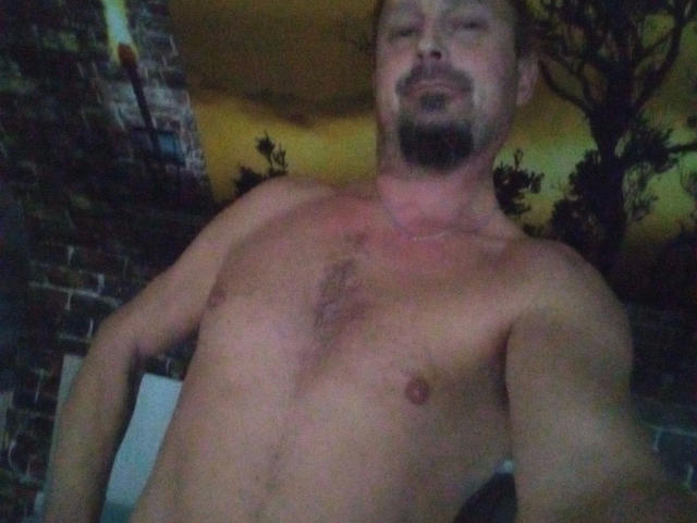 Shirtless Major-hot with a goatee, medium build, and slight chest hair, showing his bare chest and a faint red mark. His face is partially visible, smiling slightly.