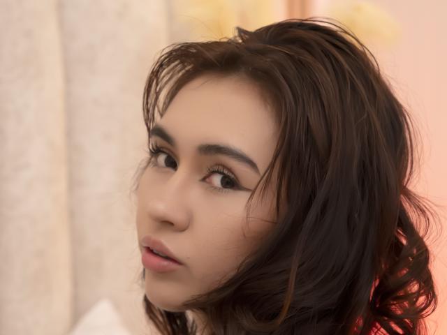 AilenTovar has medium-length, wavy brown hair, light skin, and brown eyes with long eyelashes. She's looking slightly to the side with a subtle, sexy expression.