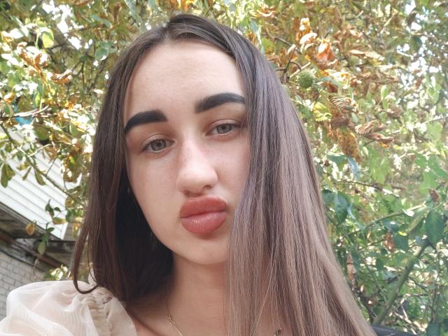 FortuneX has straight brown hair, full eyebrows, and puffy pink lips. She's looking into the camera with a neutral expression. Her skin is light with subtle freckles.