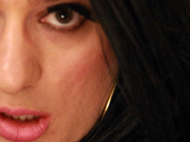 ChantalCross-hot's face, showing brown eye, pinkish lips slightly open, dark brown hair, gold hoop earring, light skin with subtle redness on cheek, close-up shot.