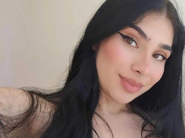 EmmaCollinsHot with long black hair, brown eyes, and a nose ring, smiling softly. She's got a cute face and subtle makeup, showing off her pinkish lips.