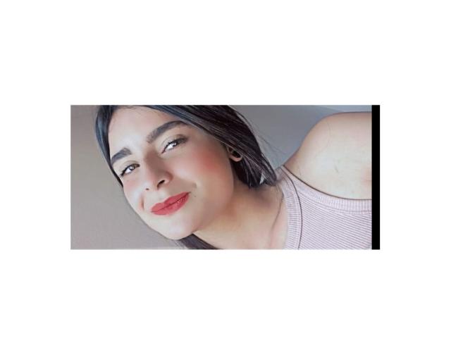 EmmaHottiestX with red lips, black hair, and a pink ribbed tank top, smiling at the camera, showing her shoulder. She has light skin and small earrings.